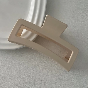 Detailed view of an oversized matte beige rectangular claw clip on a ceramic tray