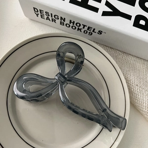 Detail showing elegant translucent dark grey bow hair claw with high-quality resin finish