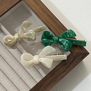 Three-piece acetate bow hair clip set in pearl, emerald marble, and cream colors