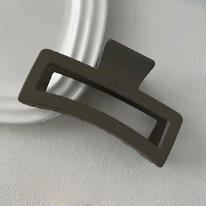 Detail view of large matte dark grey square hair claw clip on a white ceramic plate