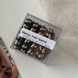 Detail view of 8-piece braided hair bands in neutral tones inside a clear storage box