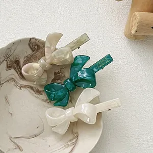 Elegant acetate bow hair clips in green, beige, and white colors with marble texture