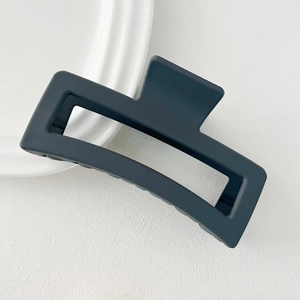 Detailed view of large matte black square hair claw clip on white textured background
