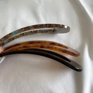 Close-up of minimalist U-shaped resin hair pins in marble, amber, and black finishes