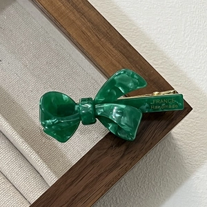 Close-up of green marble acetate bow hair clip with gold France Handmade logo engraving