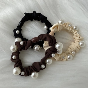 Close-up of elegant pearl hair ties in black, dark brown, and beige crinkle fabric