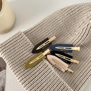 5-piece set of colorful acetate hair clips with gold logo on a white knit beanie background