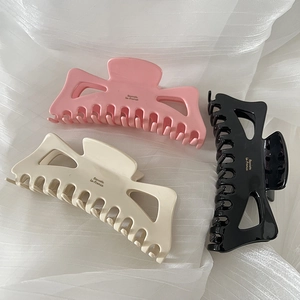 French style oversized bow hair claws in pink, cream, and black colors on white fabric