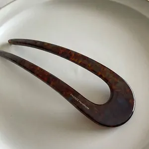 Macro detail of French handmade tortoise shell U-shaped hairpin with golden engraving