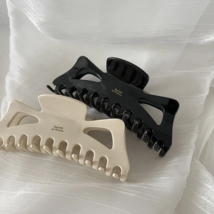 Close-up of large bow-shaped hair claws in black and cream with gold Barrette La France text