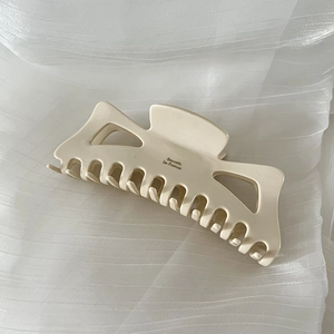 Macro detail of creamy white hollowed-out hair claw clip with golden Barrette La France text