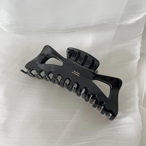 Detail view of large black glossy hair claw clip featuring golden Barrette la France text