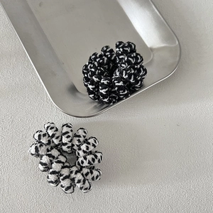 Thick checkered spiral hair ties in black and white pattern on a metal tray