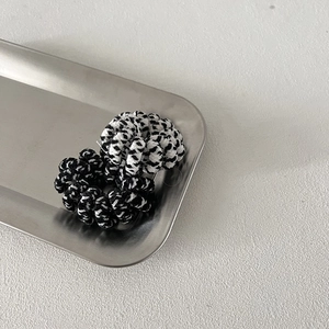 Chic black and white checkered knit spiral hair ties on a sleek stainless steel tray