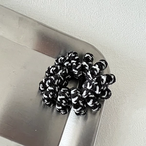 Detail shot of black and white polka dot woven telephone wire hair tie on a silver tray