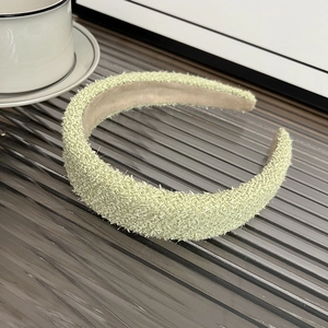 Detail of light green thick tweed headband on a gray tray with a ceramic cup