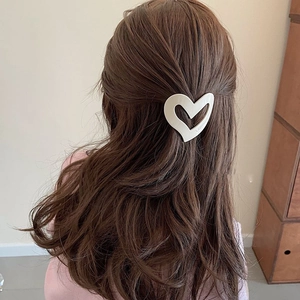 Irregular cream heart hair clip with hollow design worn on long wavy hair
