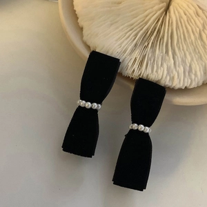 Elegant pair of black velvet bow earrings with pearl inlay on a white shell plate