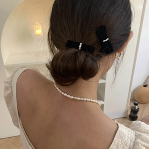 Elegant velvet bow hair clips with white pearls shown on a low bun hairstyle