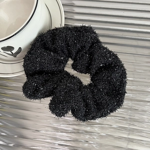 Detailed macro view of black fuzzy scrunchie with sparkling silver metallic thread texture