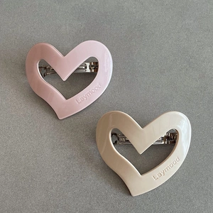 Detailed close-up of cream and pink hollow heart hair clips with Laymood engraving