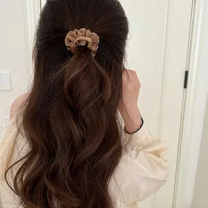 Brown satin scrunchie on a half-up ponytail showing smooth silk texture and elastic stretch