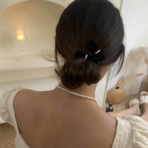 Close-up of black velvet bow hair clips with pearls on an elegant bun hairstyle