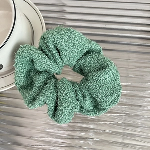 Detail of Morandi green knit hair scrunchie with fuzzy texture on a metal tray