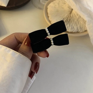Detail of elegant black velvet bow hair clips with delicate white pearls in a pair
