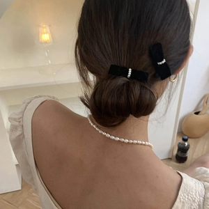 Detail view of velvet bow hair clips with pearls on a model's elegant hairstyle