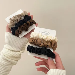 Close-up of three-piece satin scrunchies in coffee tones on a display card for hair styling