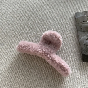 Gros plan sur la pince à cheveux en peluche rose sur un tapis doux avec un magazine