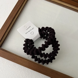Detailed view of three black elastic spiral hair ties with 'nice day' branded card tag