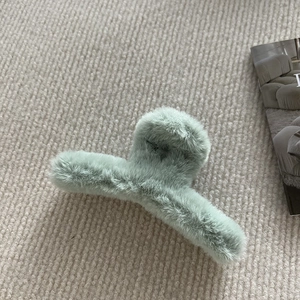 Gros plan sur la grande pince à cheveux en peluche vert menthe et fausse fourrure