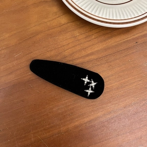 Detailed shot of black velvet hair clip with silver rhinestone star patterns on wood