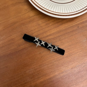 Detail of silver star rhinestones on a black velvet headband over a vintage wooden table