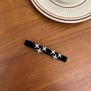 Detail of black velvet hair clip with silver rhinestone stars on a wooden surface