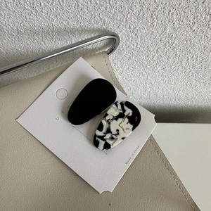 Détail de pinces à cheveux élégantes en acétate noir et texture marbre sur carte