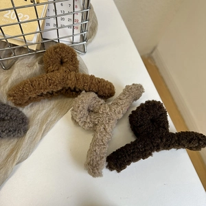 Close-up of plush faux fur claw clips in various earth tones for winter hairstyles