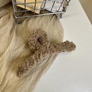 Macro detail of brown plush hair claw clip showing fluffy lamb wool texture on fabric