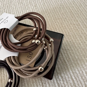 Close-up of elastic hair ties with gold beads in black, beige and coffee colors