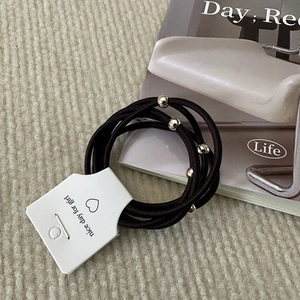 Detail of 5-piece brown elastic hair ties with silver metal beads on a display card