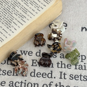 Close-up of acetate mini hair claws in various colors on a vintage fabric background