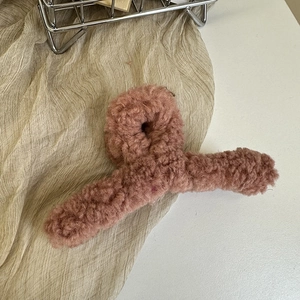 Detail shot of plush faux shearling hair claw clip in a warm dusty rose pink color
