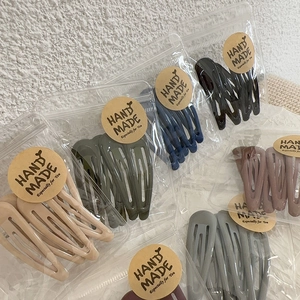 Close-up of matte minimalist hair clips in diverse colors packaged in handmade craft bags