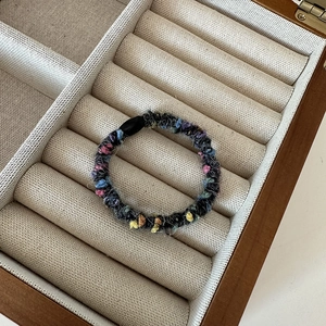 Detail of colorful plush hair tie with pink and blue yarn in a wooden jewelry box