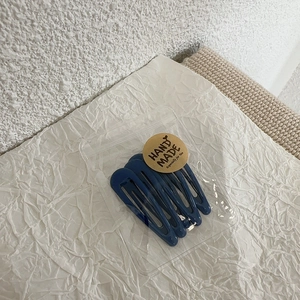 Detailed view of five navy blue drop-shaped metal BB hair clips in craft packaging