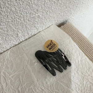Close-up of 5-piece black teardrop BB clips in handmade style packaging on woven mat