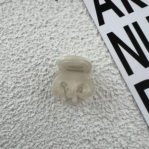 Detailed close-up of cream-white acetate hair claw with gold FRANCE Handmade lettering