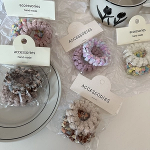 Plush knit hair rings set in beige and purple tones on white background with floral decor